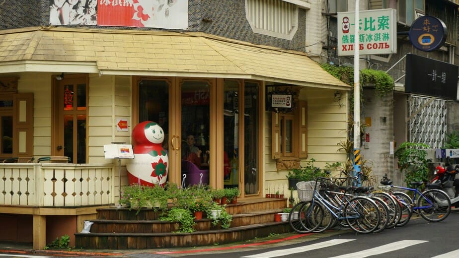 茶色の木製のドアの脇に停められた黒いシティバイクの画像